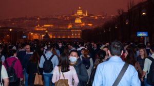 Oameni migrând spre un oraș european iluminat.